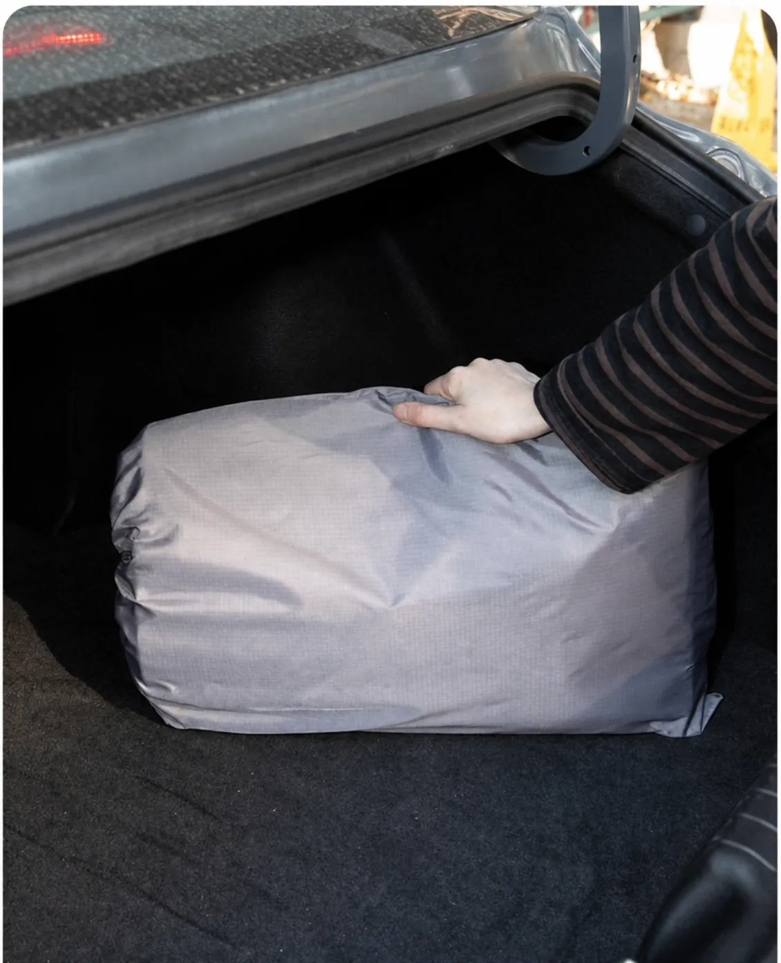 Folded pet car hammock stored in a vehicle boot