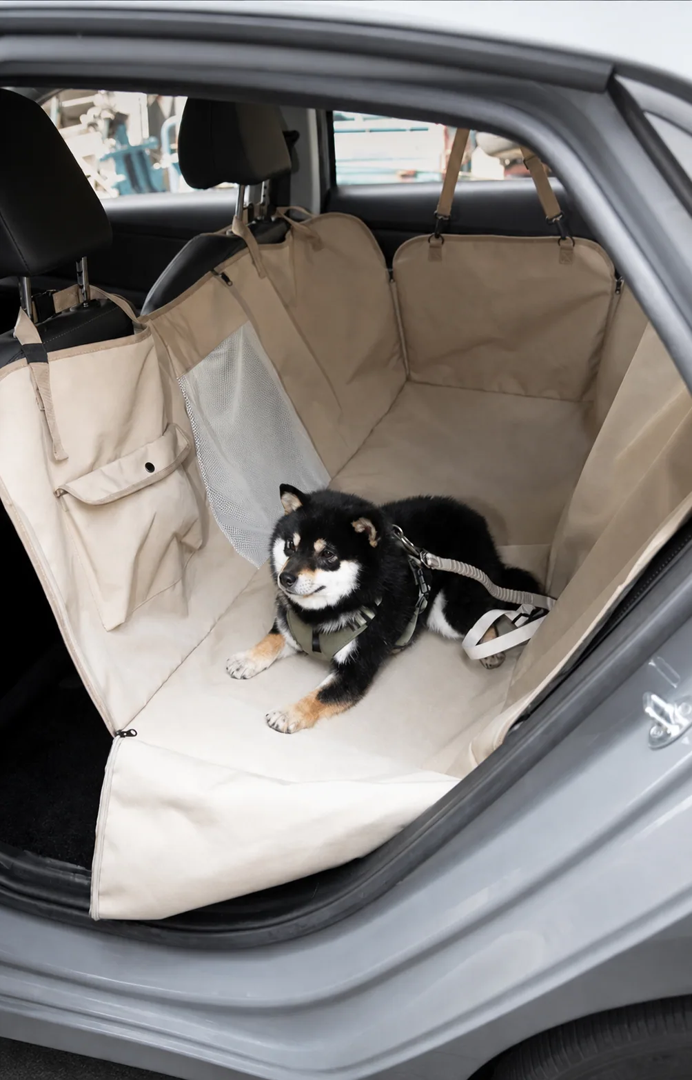 Full-coverage khaki brown pet car hammock installed across a rear seat